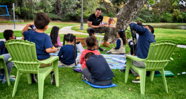 GySgt Brad Phillips reads a book about dinosaurs to chidren attending the Oceanside Promise Love of Literacy event at Libby Lake Park